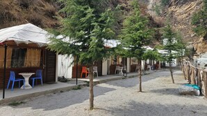 Eine Reihe von Ferienhäusern mit Sitzgelegenheiten im Freien, umgeben von Bäumen und Bergen.