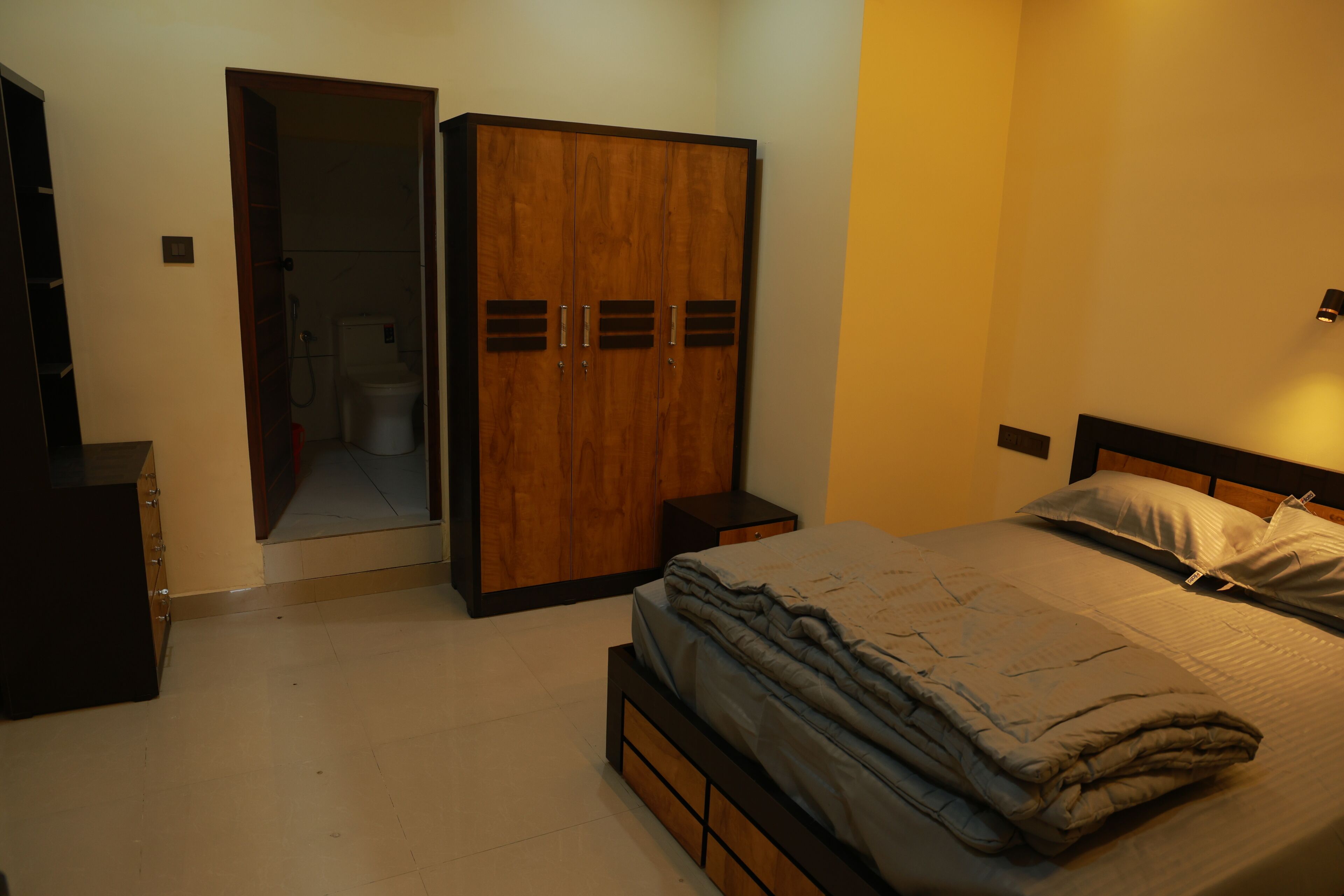 Een slaapkamer met een bed, een kledingkast en een klein nachtkastje.
