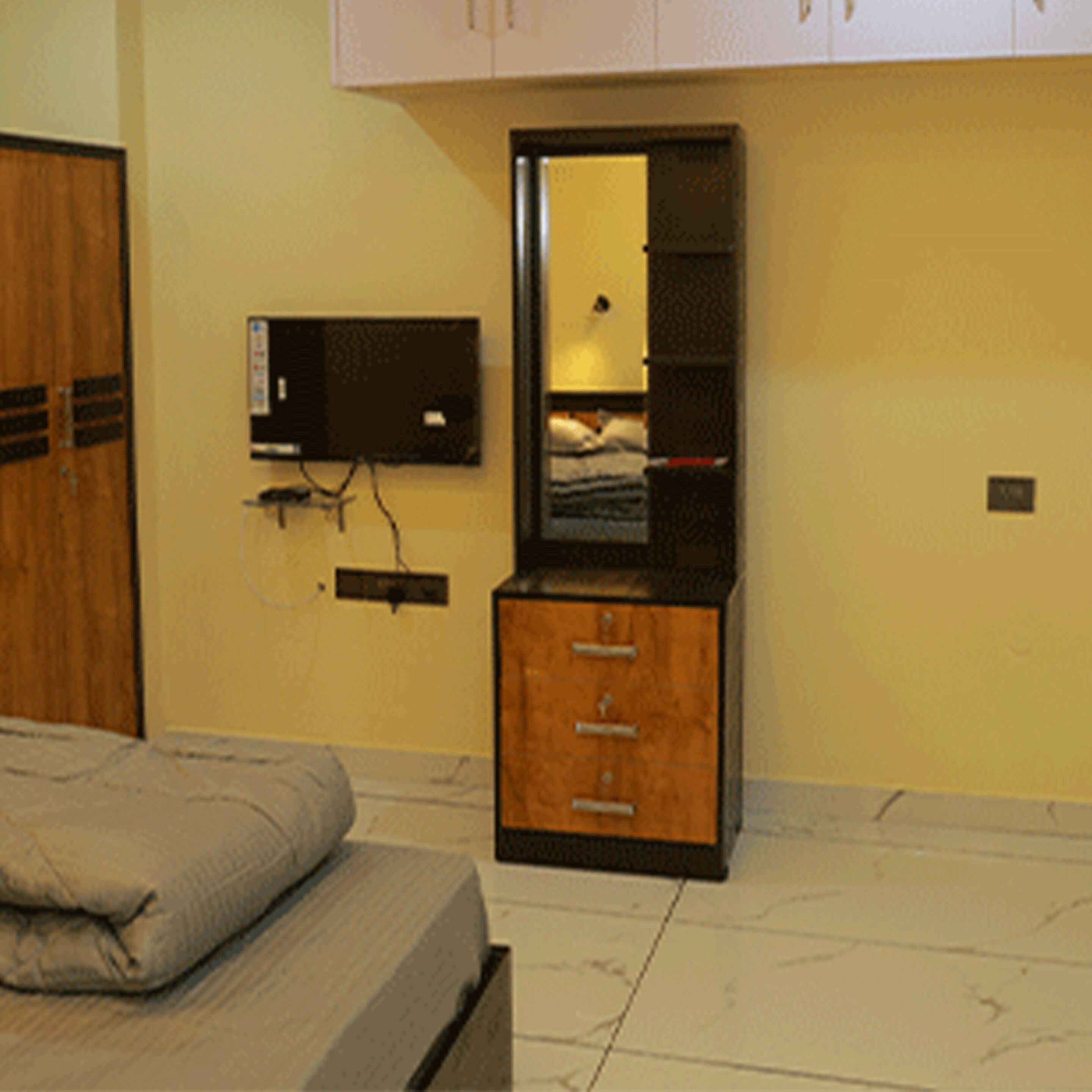 Un dormitorio con una cama, un aparador de madera, un espejo y un televisor montado en la pared.
