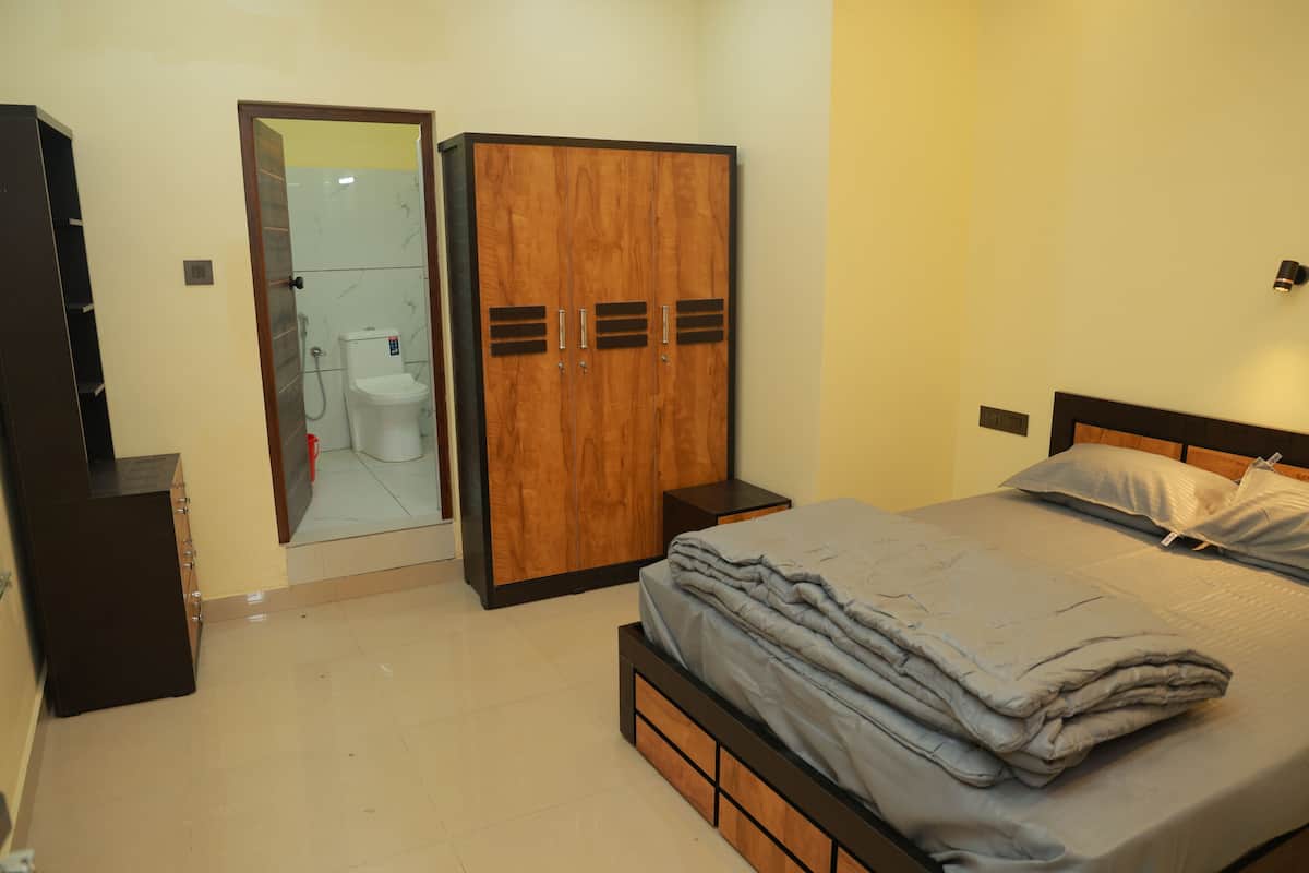 Un dormitorio con cama, armario, espejo y un inodoro.