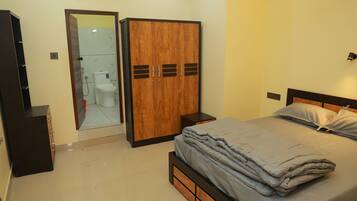 A bedroom with a bed, a wardrobe, a mirror, and a toilet.