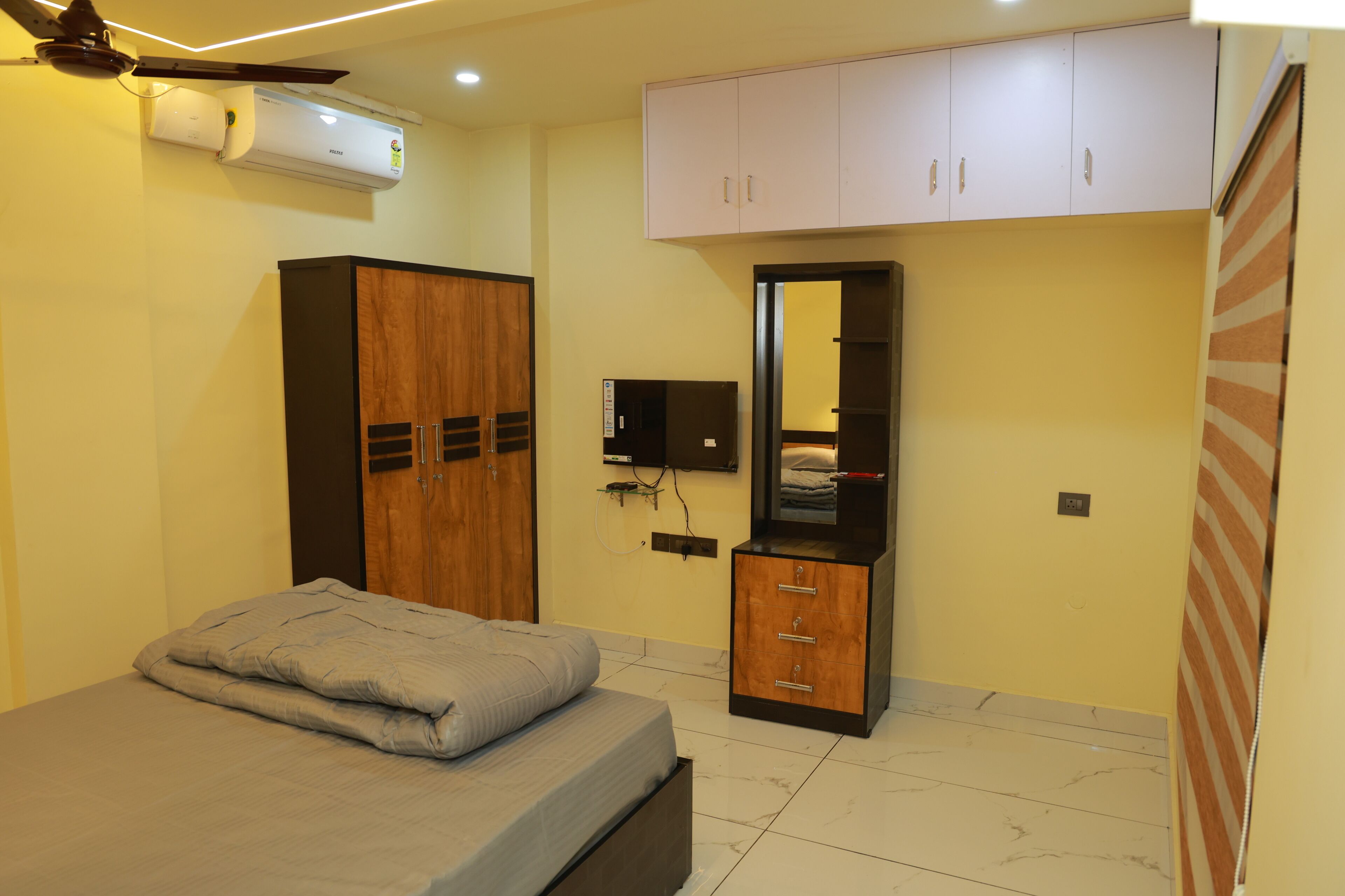 A bedroom with a bed, wardrobe, mirror, and ceiling fan.