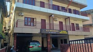 A multi-story building with a sign for 'SJ Homes' advertising AC and non-AC rooms. - SJ HOMES  (Changanassery)