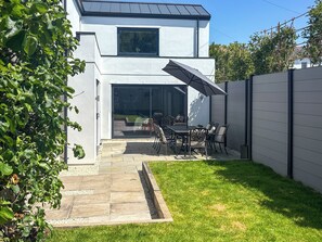 A modern two-story house with a patio area featuring a dining table and chairs, a sliding glass door, and a view of the backyard. - 3 bedroom accommodation in Plymouth (Plymouth)