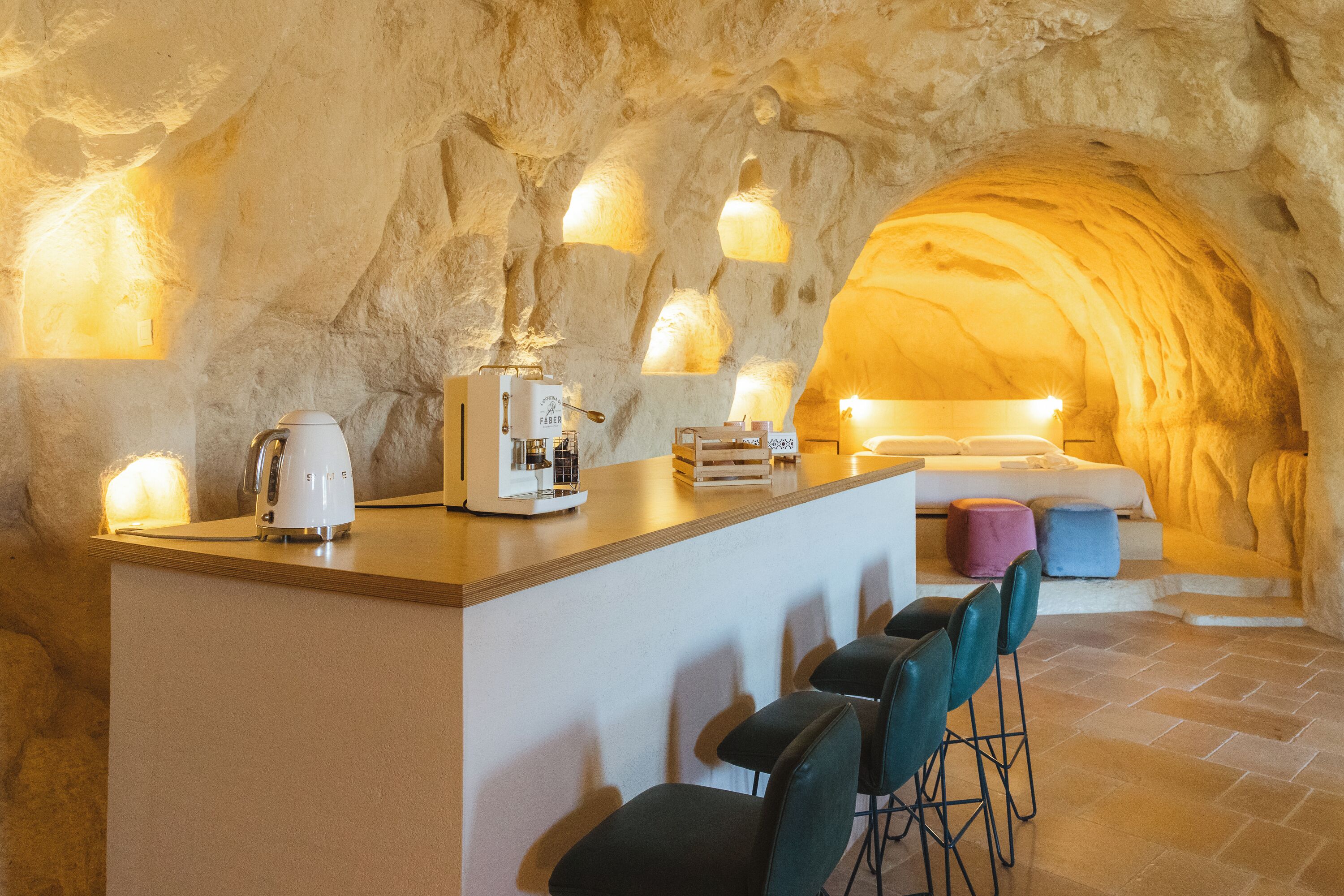 A cozy interior with a stone wall, a bar area with stools, and a bed with pillows.