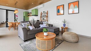 A modern living room with a grey sofa, round coffee table, and rattan ottoman. - Darani Villa by Kozystay - Ungasan (Ungasan)