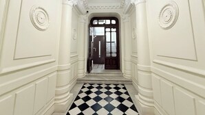 A hallway with white walls, a black and white checkered floor, and a door at the end. - Ze Perfect Place - Centre - Durandy - 2 Bdrms - AC (Nice)