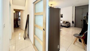A modern interior with a hallway leading to a living area, a sliding door, and a sofa. - Ze Perfect Place - Centre - Durandy - 2 Bdrms - AC (Nice)