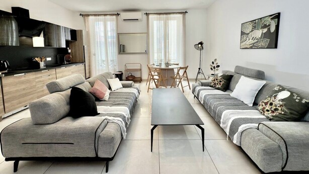 A modern living room with grey sofas, a coffee table, and a dining area with a table and chairs. - Ze Perfect Place - Centre - Durandy - 2 Bdrms - AC (Nice)