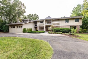 A two-story house with a garage, a covered front porch, and a landscaped front yard. - New Luxury Waterfront Retreat with Pool, Private Pier & Multiple EnSuite King Bedrooms (Annapolis)