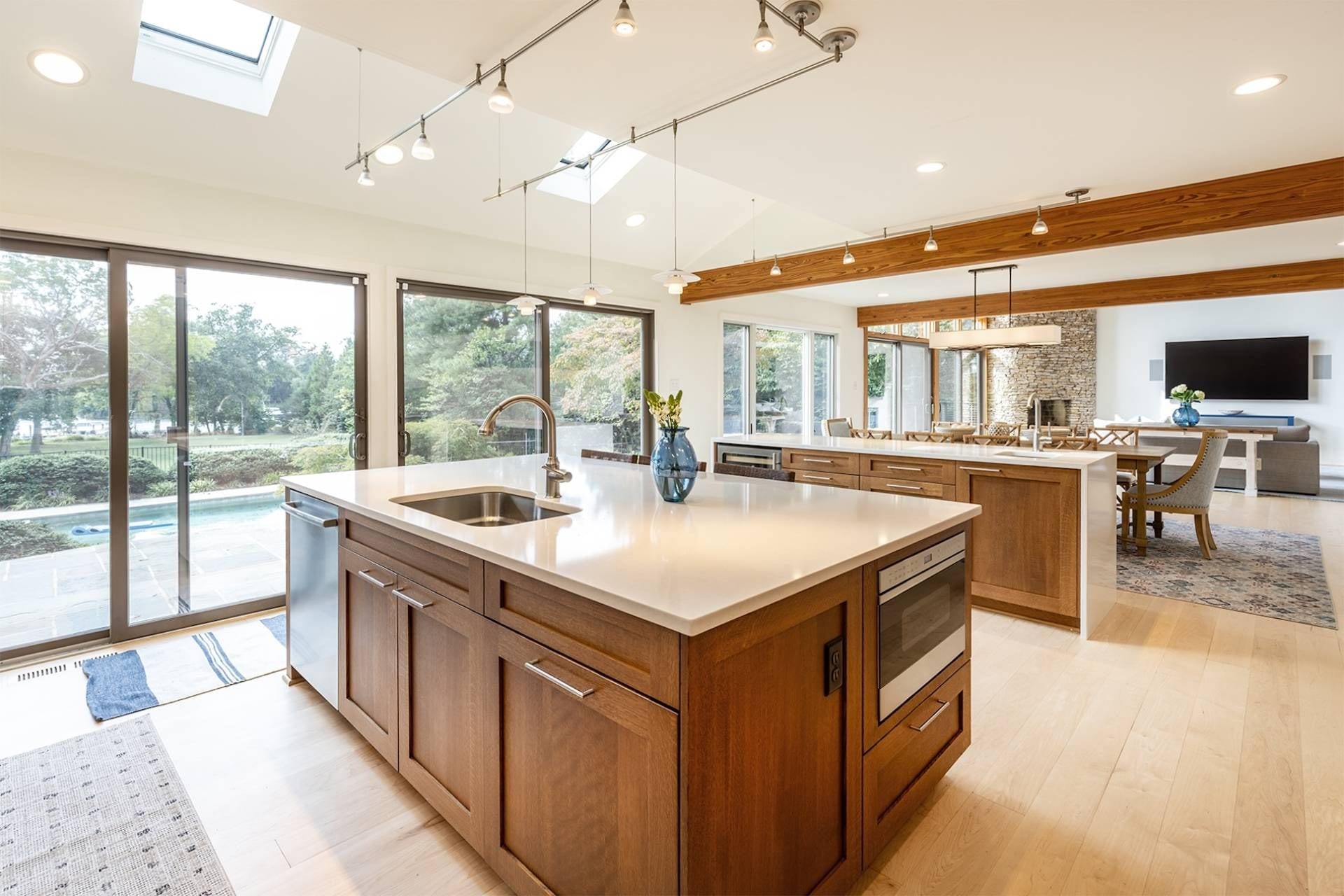 A modern kitchen with a large island, wooden cabinetry, and a view of the outdoors.