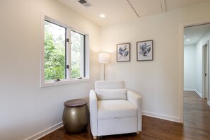 A room with a white armchair, a floor lamp, and two framed floral artworks on the wall. - New Luxury Waterfront Retreat with Pool, Private Pier & Multiple EnSuite King Bedrooms (Annapolis)
