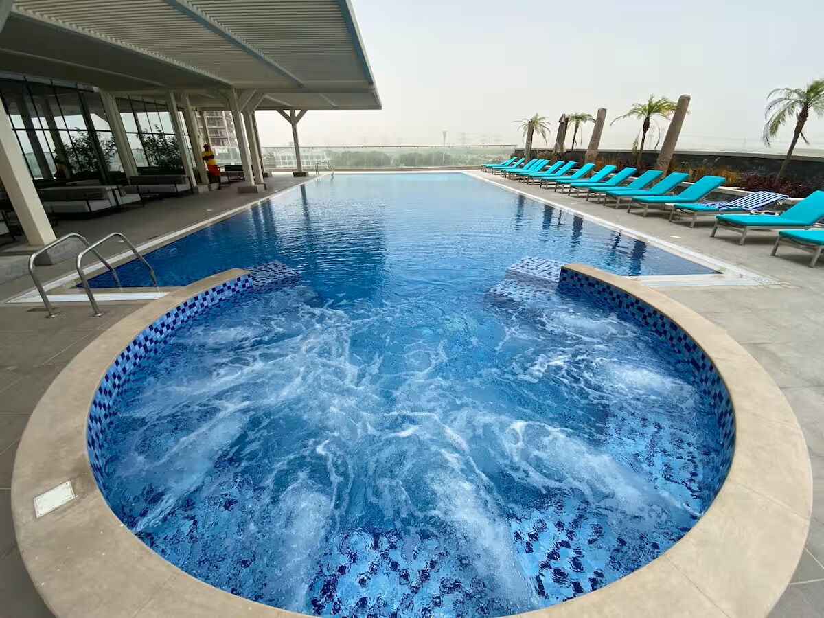 Piscina com hidromassagem, espreguiçadeiras e área de estar coberta.