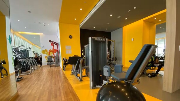 Ein Fitnessraum mit Trainingsgeräten, einem großen Spiegel und Holzboden.