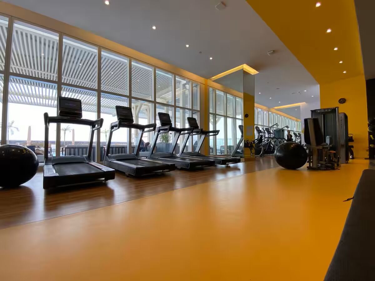A gym with treadmills, exercise balls, and a large windowed wall.