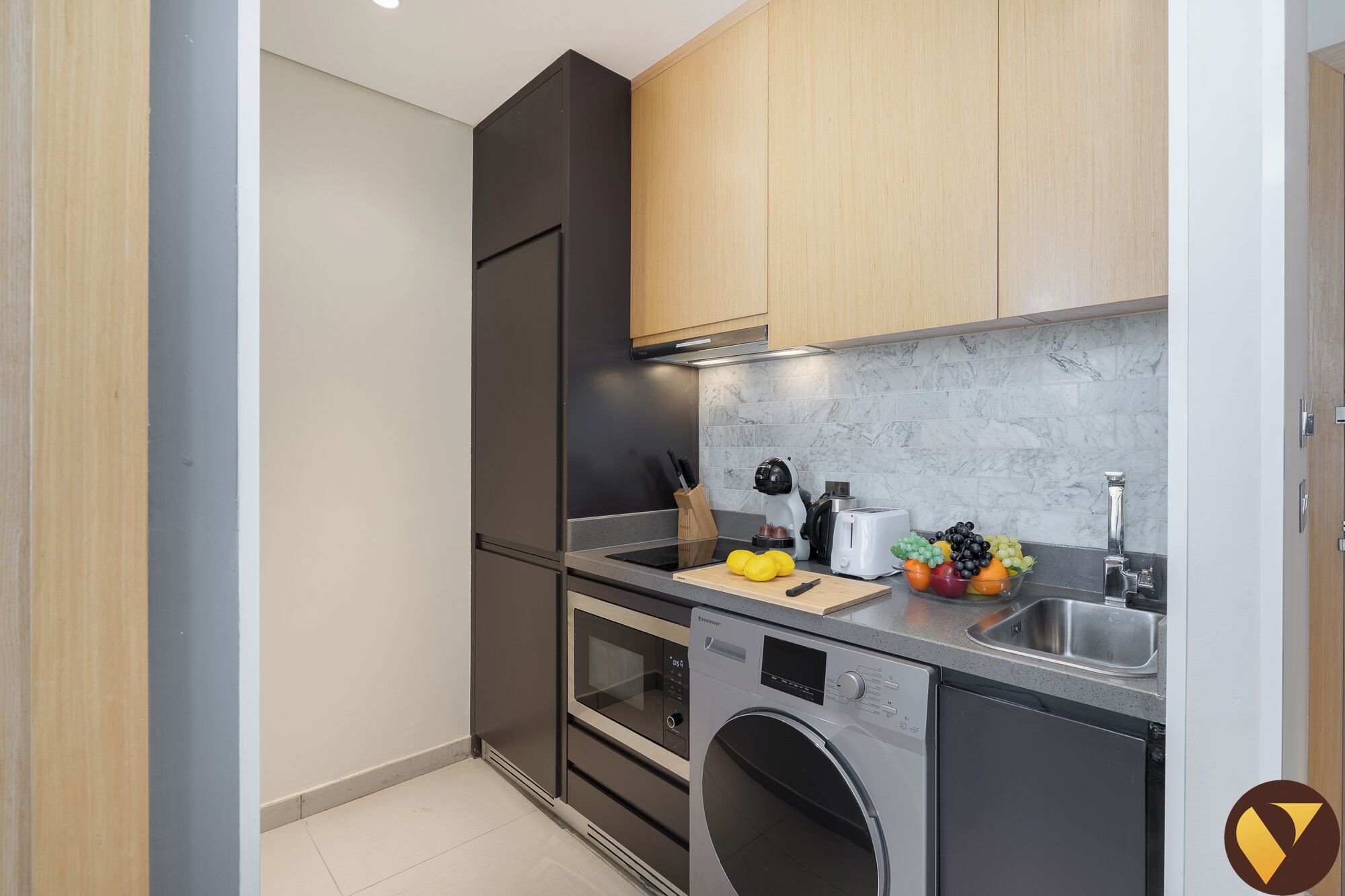 A compact kitchen with a washing machine, a microwave, and a sink.
