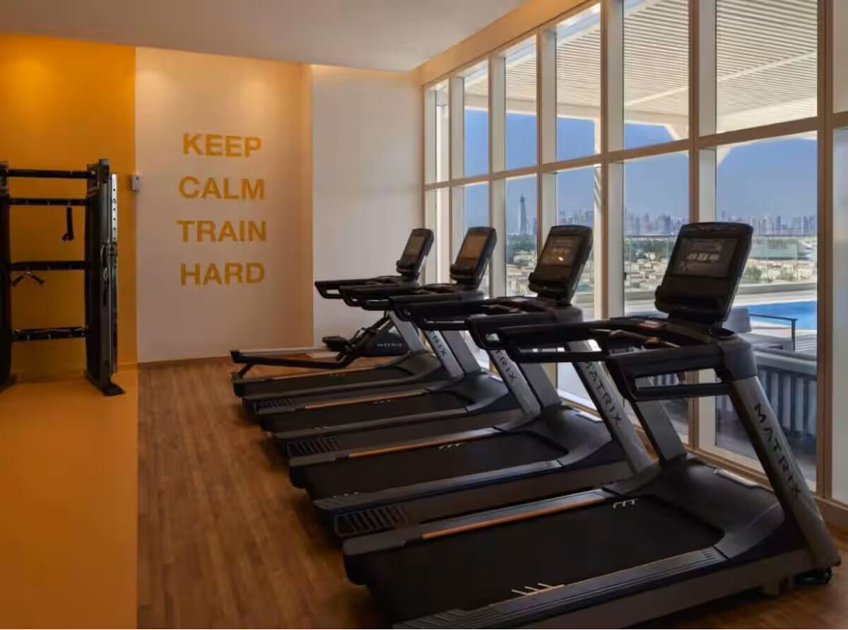 A gym with treadmills, a pull-up bar, and a motivational quote on the wall.