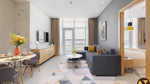 A modern living room with a grey sofa, a small coffee table, and a dining area with a round table and chairs. - Vogue | JVT near Springs Souk Mall (Dubai)