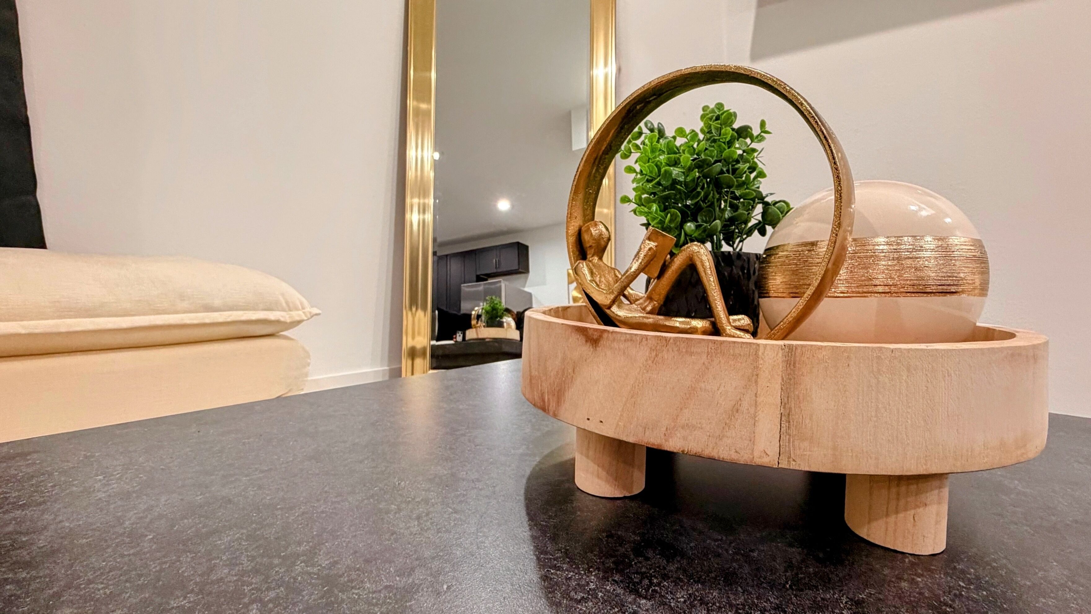 A wooden tray with a plant and decorative items on a dark countertop.