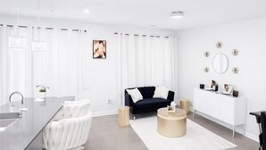 A modern living room with a black sofa, white curtains, a round coffee table, and a white cabinet. - Luxury 3BR 3.5BA Townhome Near Uptown & Stadium (Charlotte)