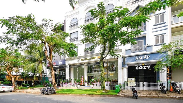 A multi-story building with a white facade, balconies, and a mix of commercial and residential spaces. - The Shilla Hotel - 신라호텔 (Ho Chi Minh City)