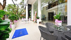 A hotel lobby with a glass entrance, indoor plants, and a blue welcome mat. - The Shilla Hotel - 신라호텔 (Ho Chi Minh City)
