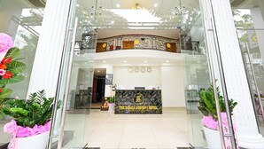 A hotel reception area with a marble counter, a chandelier, and potted plants. - The Shilla Hotel - 신라호텔 (Ho Chi Minh City)