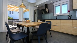 A modern kitchen with a wooden table, blue chairs, and a fruit bowl. - Villa Lumaka Sun by Villas Guide (Sibenik)