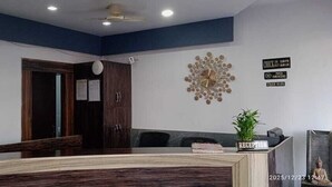A reception area with a reception desk, a clock, a sign indicating no smoking, and a decorative wall piece. - The Bhuwan Heights Inn (Satna)
