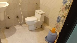 A small bathroom with a toilet, sink, and shower. - The Bhuwan Heights Inn (Satna)