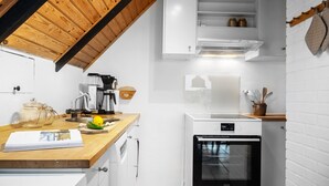 A modern kitchen with white cabinetry, a wooden countertop, a built-in oven, and a coffee maker. - 2 bedroom pet friendly home in Thisted (Thisted)