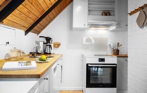 A modern kitchen with white cabinetry, a wooden countertop, a built-in oven, and a coffee maker. - 2 bedroom pet friendly home in Thisted (Thisted)
