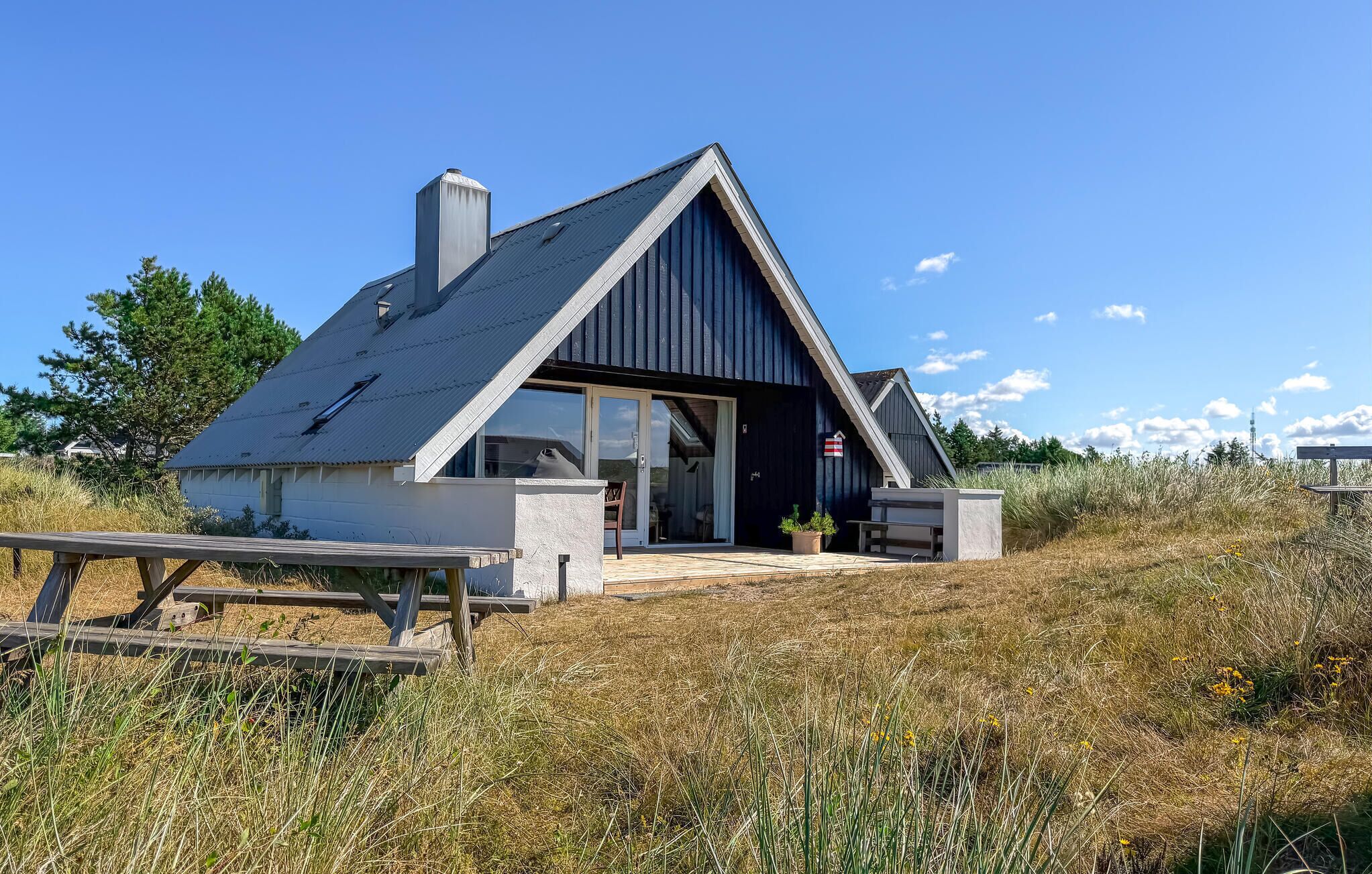 Ein modernes Haus mit Satteldach, Schornstein und einem großzügigen Eingang mit Glastür.