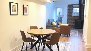 Un comedor con una mesa redonda y sillas, un tapete floral y dos cuadros en la pared.