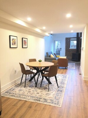 A dining area with a round table and chairs, a floral rug, and two framed artworks on the wall. - 2-Story Garden Loft with Parking - 1200 Sqft, 2BR/3Qeen Beds, Walk to Metro, Zoo (Washington)