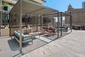 A rooftop terrace with outdoor seating, a TV screen, and a view of a historic building in the background. - 41st Floor! 2BDR w/ Luxury Amenities & Balcony | SkyLux Penthouse by AvantStay (San Diego)