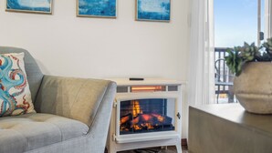 Ett vardagsrum med en soffa, en öppen spis och tre abstrakta målningar på väggen.