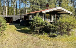 Un rustico chalet con tetto in metallo, immerso in una fitta foresta.