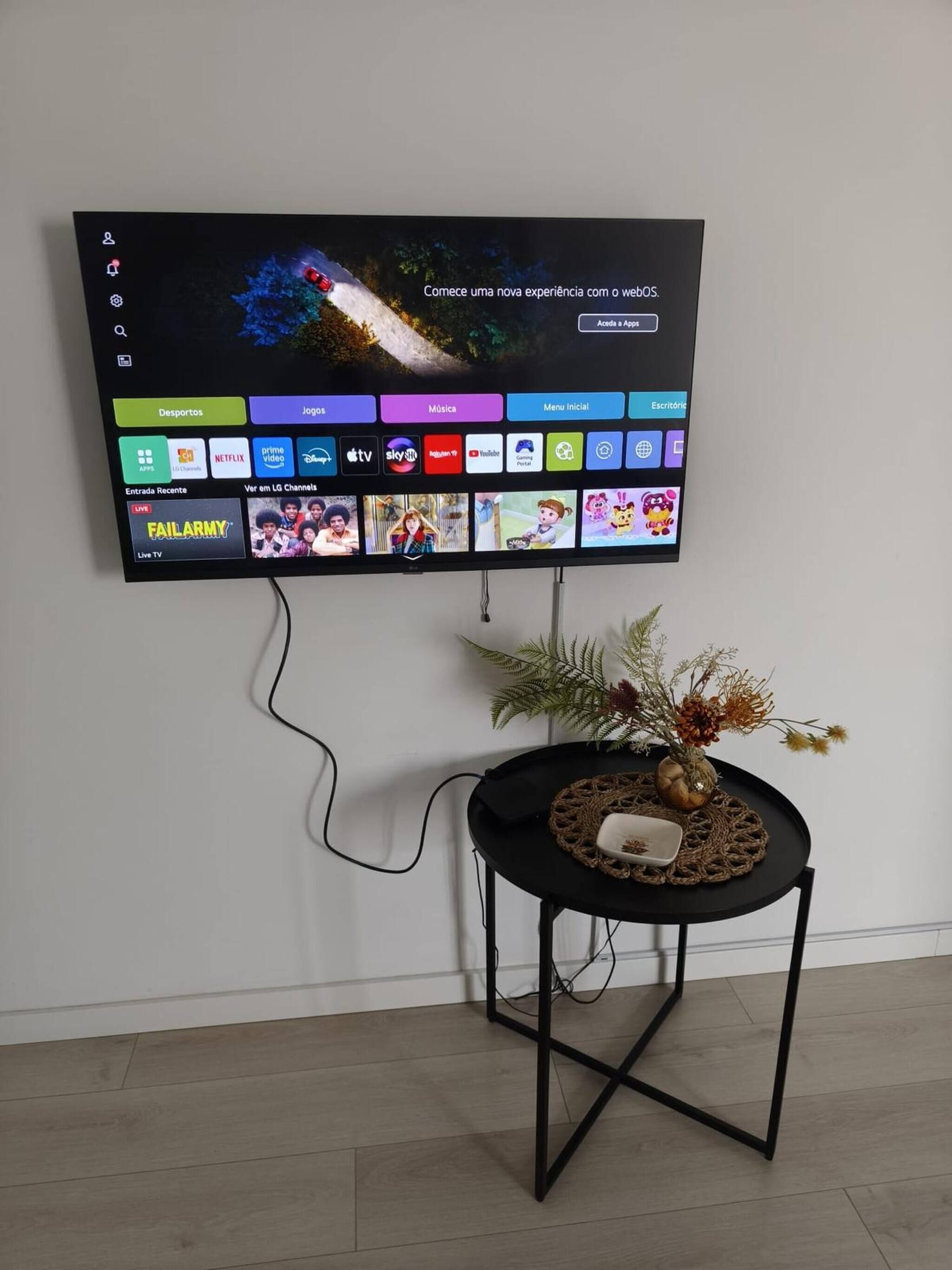 Televisão de tela plana fixada na parede, com um cabo conectado.