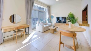 Un salon moderne comprenant un canapé, un miroir rond, un téléviseur et un coin repas avec une table et des chaises.