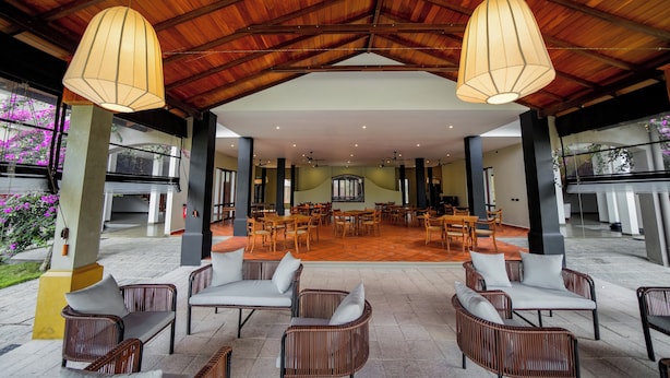 A spacious outdoor seating area with wicker furniture and pendant lighting, overlooking a dining area with multiple tables and chairs. - Adaar Kuchchaveli (Trincomalee)
