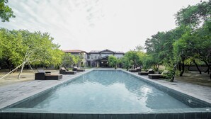 A rectangular swimming pool with lounge chairs and a covered seating area in the background. - Adaar Kuchchaveli (Trincomalee)
