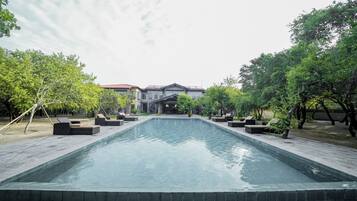 Een buitenzwembad, parasols bij het zwembad en ligstoelen