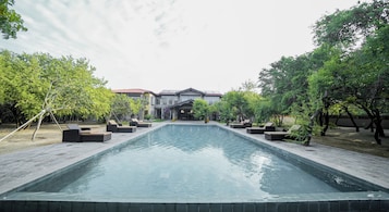 Una piscina al aire libre, sombrillas, sillones reclinables de piscina