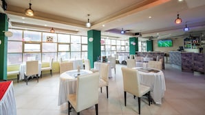 A restaurant with round tables, chairs, and a bar area. - Capital Comfort Hotel (Nairobi)