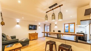 Een moderne keuken met een houten aanrecht, barstoelen en hanglampen.