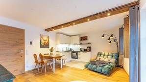 Un espacio habitable moderno con comedor, cocina y una zona de estar acogedora con un sofá verde.