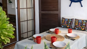 Un comedor con una mesa dispuesta para dos, una rueda de barco en la pared y una puerta corredera que da a otra habitación.