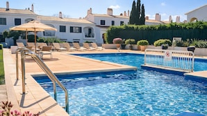 Una piscina con sillas de descanso, una escalera metálica y un letrero de prohibido bañarse.