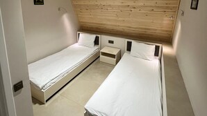 A small, modern bedroom with two single beds, a wooden sloped ceiling, and a small bedside table between them. - AFORREST FAMILY RESORT (Qusar)